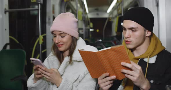 Millennial Guy Using Reading Book While Sitting Near His Lovely Girlfriend. Young Pretty Girlusing