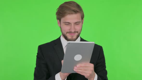 Young Businessman Using Digital Tablet on Green Background