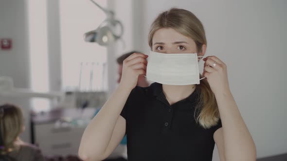 A female dentist puts on a protective mask and looks into the camera.The work of a dentist. 