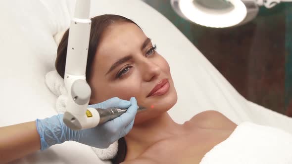 Girl with Perfect Skin Receiving Facial Treatment on Cheek with Erbium Laser