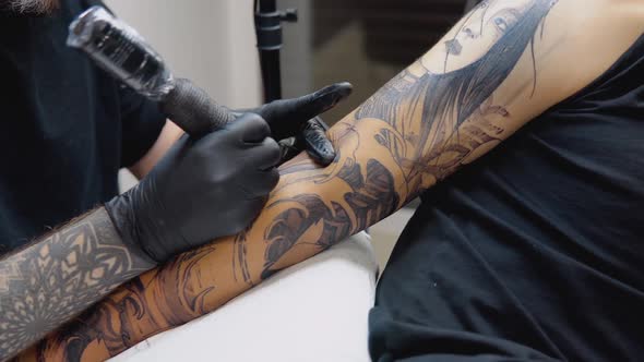 A Tattoo Artist with a Tattooed Arm Makes a Full Arm Tattoo to His Client