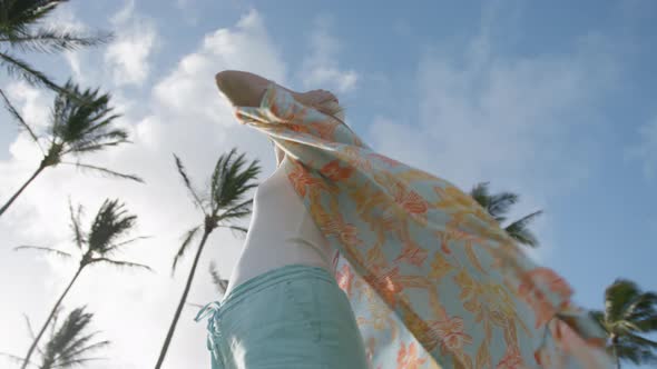 Attractive Woman with Raised Hands Beach Cover Flattering on Wind at Palm Trees