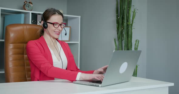 Woman Wears Headset Conference Calling on Laptop Talks with Online Teacher Studying from Home