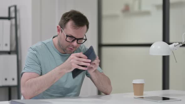 Young Man Checking Empty Wallet at Work