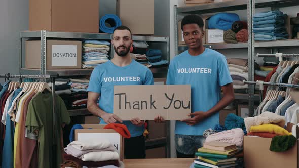 Portrait View of the Diverse Male Volunteers Holding Cupboard Banner with Thank you Phrase and