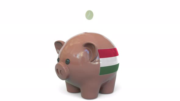 Putting Money Into Piggy Bank with Flag of Hungary alt