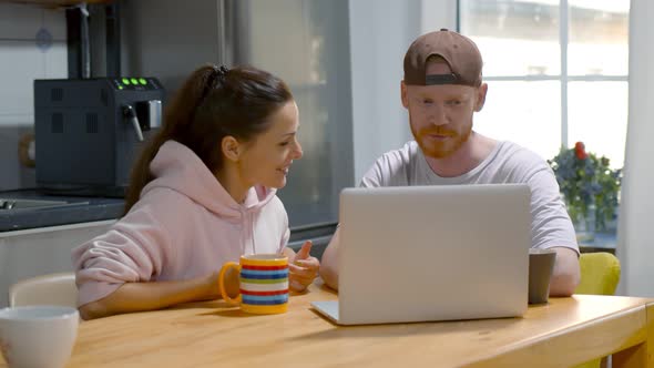 Happy Couple Drink Coffee and Using Laptop Relax Together at Kitchen at Home