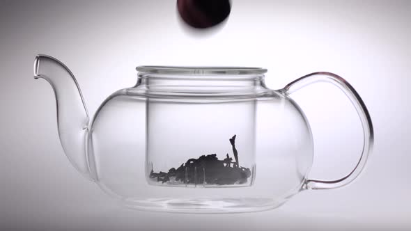 Two Tablespoons of Tea Poured in Transparent Teapot. White Background