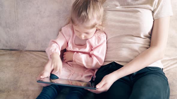 High-angle Shot, CU, : Young Attractive Mother and Sweet Daughter Are Sitting on the Couch