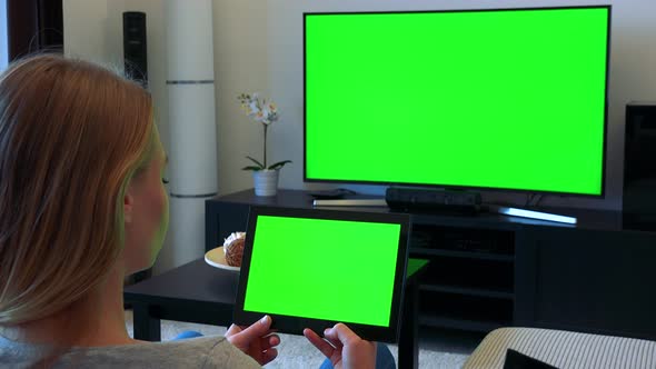 Woman Sits on Couch in Living Room and Works on Green Screen Tablet and Watches TV