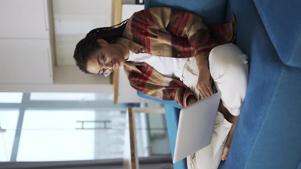 Woman with Dreadlocks is Working Using Laptop on Couch Communication Concept