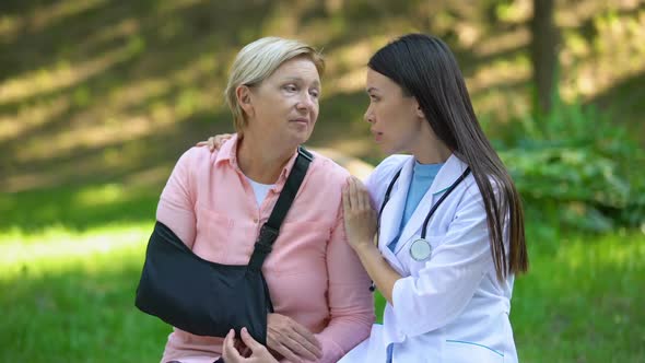 Professional Podiatrist Comforting Injured Old Lady Arm Sling, Recovery Advise