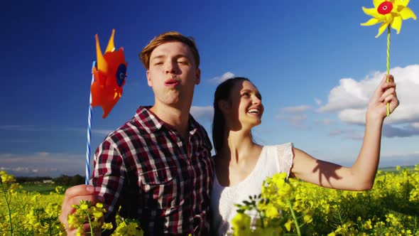 Romantic couple blowing pinwheel in mustard field