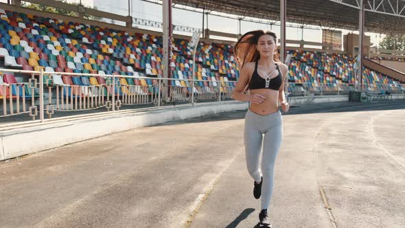 Beautiful Young Woman Jogging at Sports Stadium