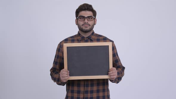 Happy Young Bearded Indian Hipster Man Holding Blackboard