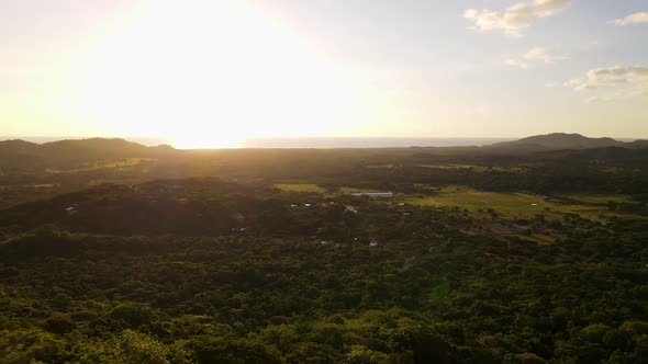 Backwardsing aerial view of a magnificent sunset over the pacific with lush and endless rainforest i