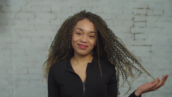 Smiling Black Woman Twisting Hair on Finger Indoors