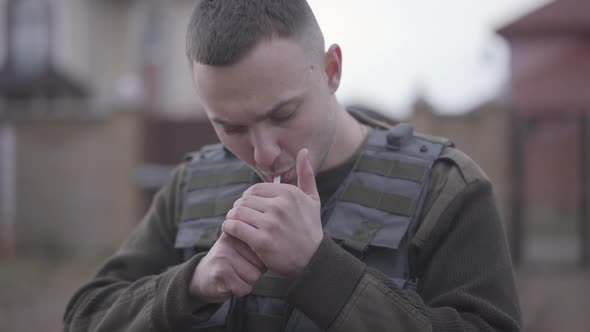 Portrait of Young Serious Military Man Setting Fire To a Cigarette, Puffing and Start Smoking