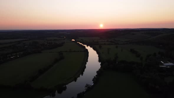 River Thames with romantic golden sunset in background, Mapledurham in UK. Aerial forward