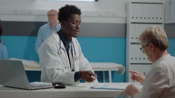 Young Medic Showing File to Old Patient for Signature