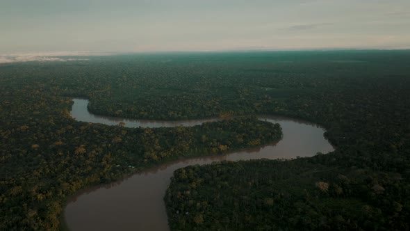 River snakes through vast tropical rainforest landscape; panoramic aerial