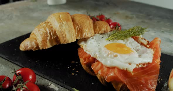 Croissant Sandwich with Cream Cheese Salmon and Egg on a Black Plate