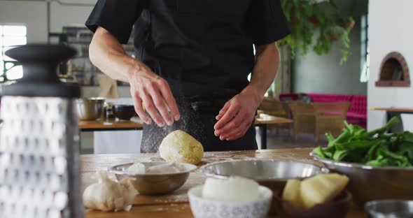 Caucasian male chef kneading dough on a kitchen table