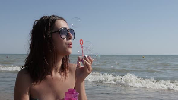 Outdoor Caucasian brunette blowing soap bubbles 4K 3840X2160 UHD video - Young  female playing with 