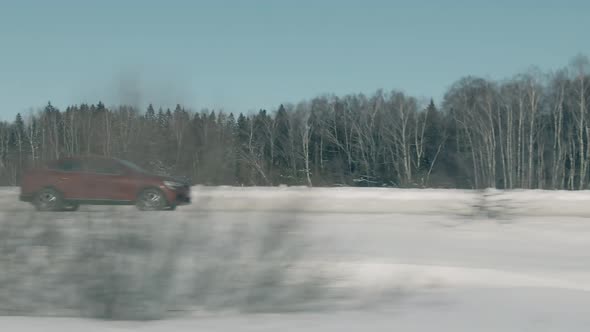 Red Car or SUV Moving in Rural Northern Area in Winter