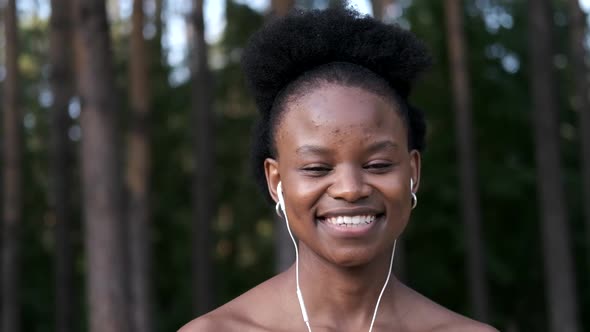 Portrait of a Young African American Woman with Headphones Listening To Music Against the Background