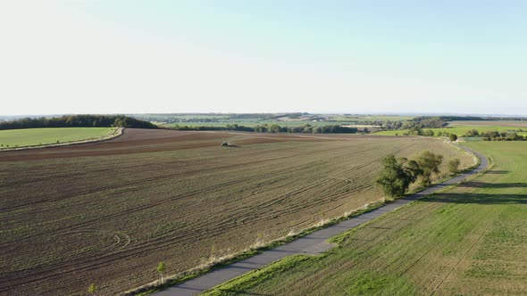 Aerial Drone Shot  a Field with a Tractor and a Road in a Rural Area on a Sunny Day