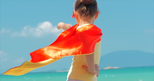 Beautiful Little Girl in the Superhero Costume, Dressed in a Red Cloak and the Mask of the Hero