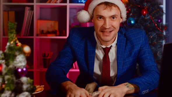 Happy Businessman in Santa Hat with Money Looking at Camera in Office