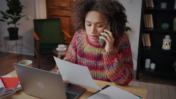 Young African American Woman Freelancer Discussing Order Details with Client Via Cellphone Working