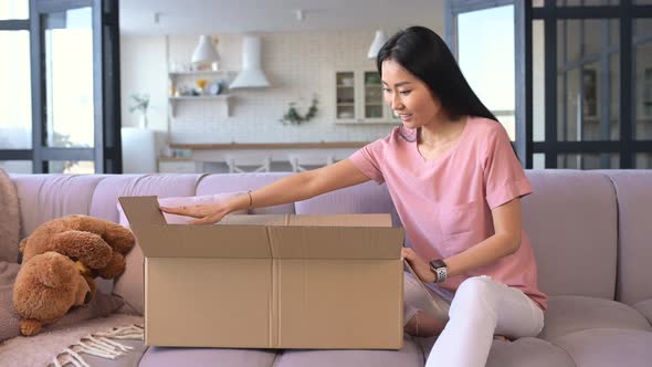 An Attractive Young Asian Woman Unpacking a Parcel Box