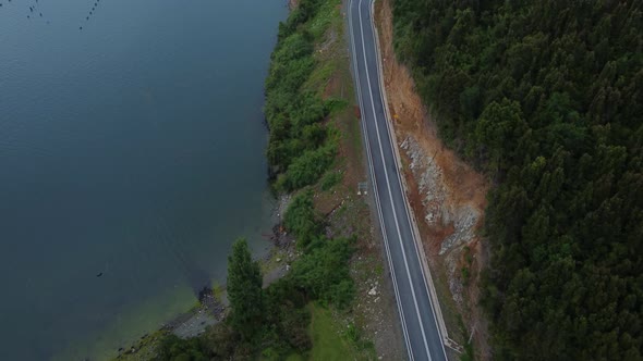 Traveling on vacation on roads between mountains, forests and lake in cloudy winter day