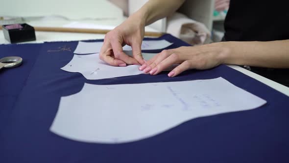 Dressmaker Pinning Sewing Patterns to Blue Fabric in Fashion Atelier