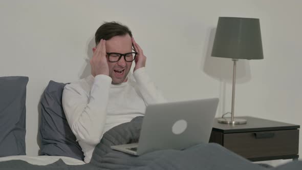 Casual Man Having Headache While Working on Laptop in Bed