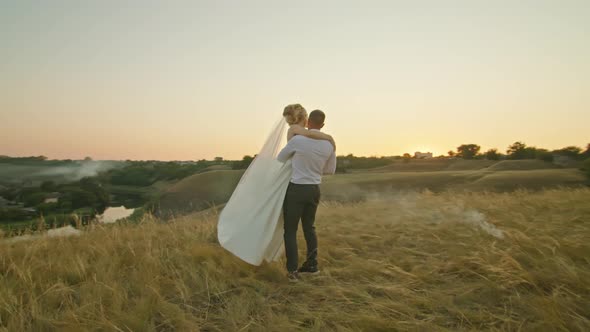 The Wedding Couple is Having Fun at Sunset on the Mountain Hills By the River