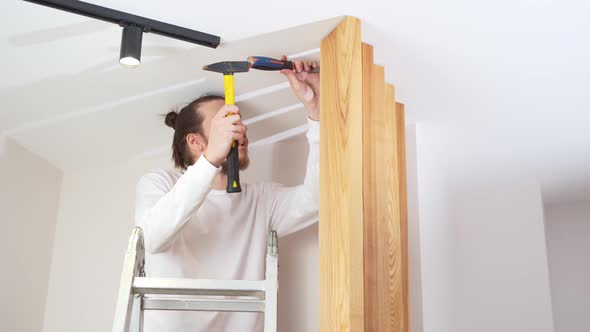 the Carpenter Nails with a Hammer Wooden Ash Lamellae to the Ceiling