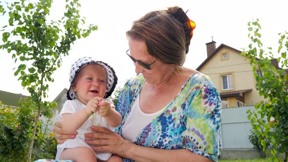 Baby girl on grandmothers hands. Grandmother with granddaughter, Mom with daughter background