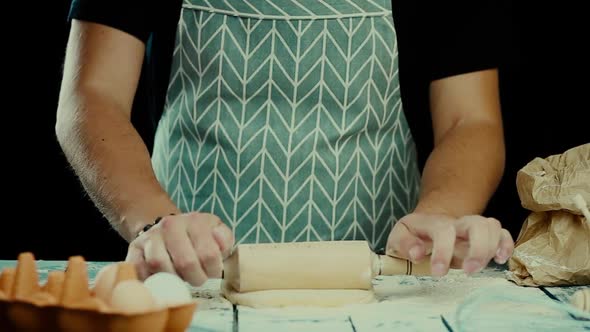 Baker Hands Preparing Fresh Dough with Rolling Pin on Kitchen Table. Man Forming the Dough on a