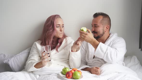 Woman Give Fresh Fruits for Breakfast To Husband They Lie on Bed Together