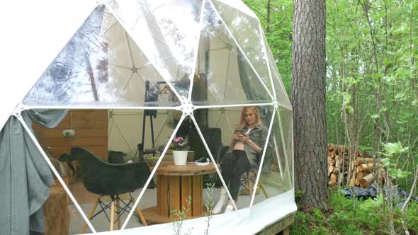 pregnant woman with phone sits in a glamping tent