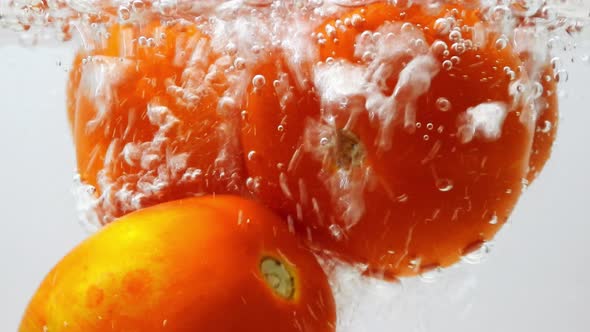 Pouring water into tomatoes in a glass pot. Static, close up