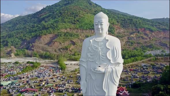 Closeup Flycam Shoots Buddha Statue Against Landscape