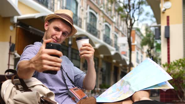 Happy Tourist Man On Vacation Taking Selfie With Coffee And Map In City