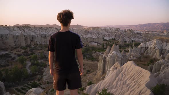 Young man walks towards a scenic viewpoint at sunset