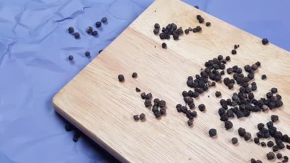 Black pepper peas roll off a wooden chopping board