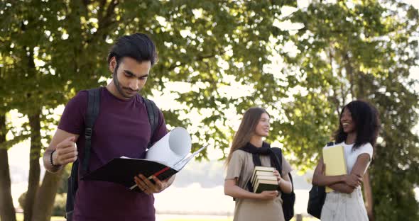 Male Student Holding Notebook and Girls Talking at Campus